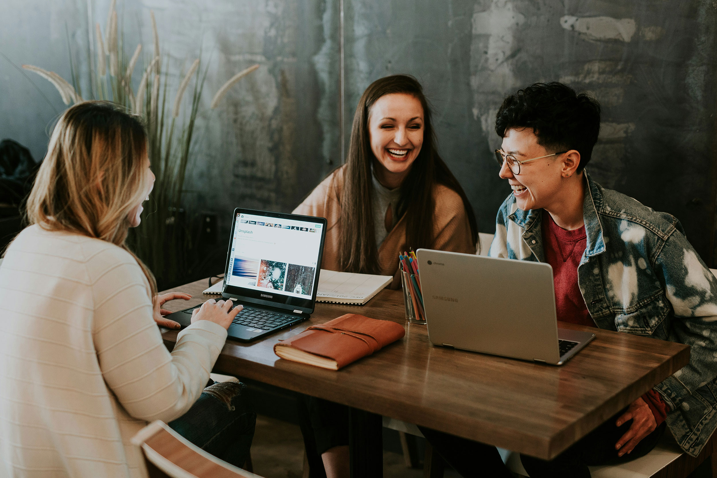 The students sit at a table happily doing schoolwork